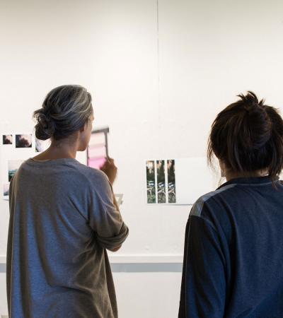 student and teacher looking at work on wall during critique