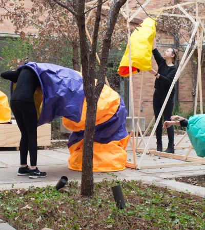 students in performance piece involving colored paper sleeves and wooden structure