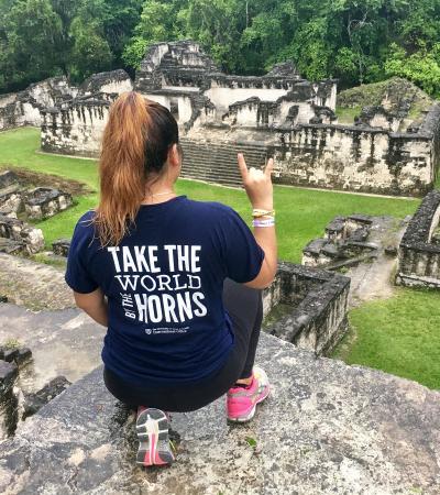 student in Longhorn short posing on pyramid in jungle