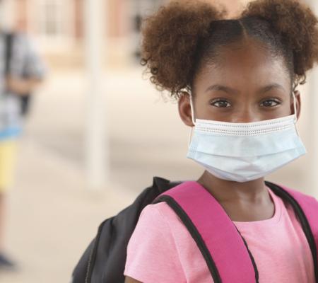 K-12 student in pigtails with mask during age of COVID-19 illustrating story about educating during pandemic from University of Texas at Austin graduate student candidate Cole Godvin