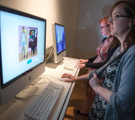 two students working on exhibition involving desktop computers