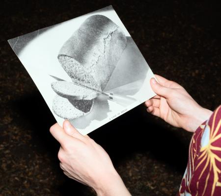 Hands holding a photograph of a loaf of bread