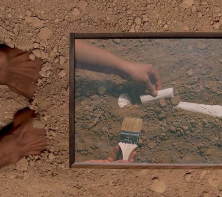 Image of hands excavating through and pushing at brown soil 