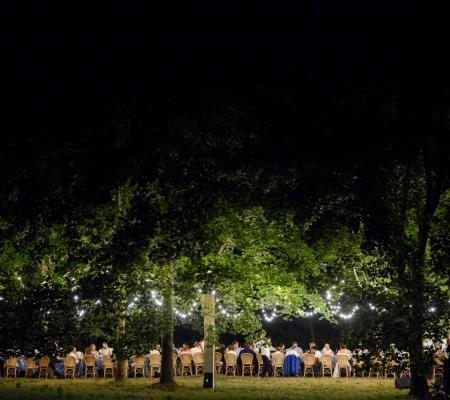 Nighttime shot of long dinner party table under lit trees