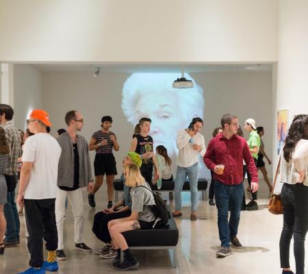 Group of people standing in an art museum in front of projected video.