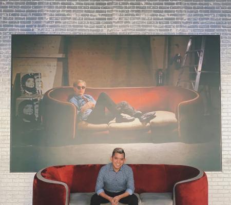 image of undergraduate in Art History Carlos Moreno in front of iconic wall at the Warhol Museum in Pittsburgh