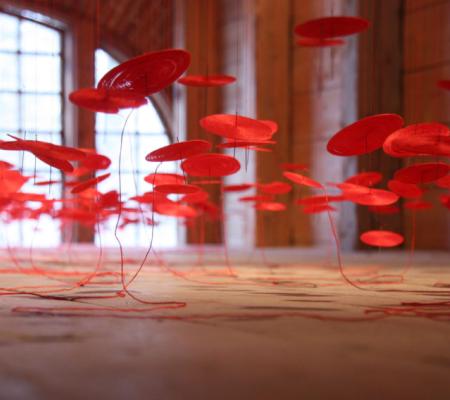 Beili Liu at the Crow Museum of Art in Dallas with an installation of hundreds of hand crafted threaded works suspended from the ceiling