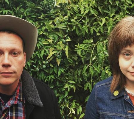 portrait of two artist in front of a garden hedge