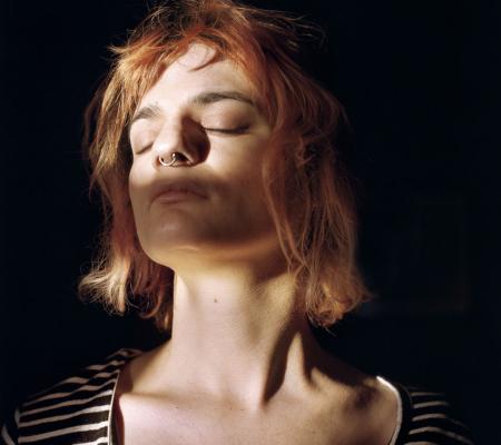 woman behind shadows cast by window blinds