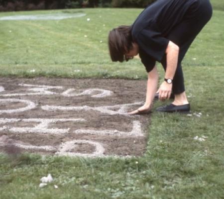 woman bending down touching grass