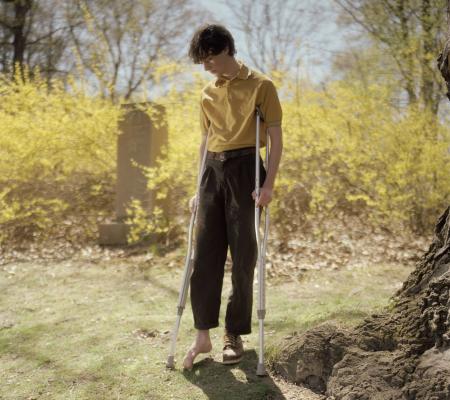 image of man on crutches at a cemetary